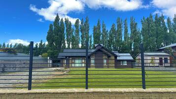 A residential area with a house, a stone wall, and a metal fence.