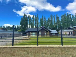 A residential area with a house, a stone wall, and a metal fence. - Increíble y amplia casa en El Calafate (El Calafate)