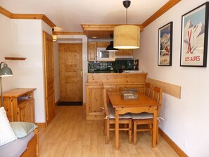 A wooden interior with a dining table, chairs, a bench, a kitchen area, and a door leading to another room. - Ideal apartment at the slope base - 4 guests (Pralognan-la-Vanoise)