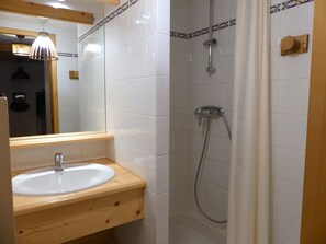 A bathroom with a wooden vanity, a sink, a mirror, and a shower with a handheld showerhead. - Ideal apartment at the slope base - 4 guests (Pralognan-la-Vanoise)