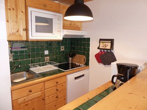 Keittiössä on puukehikoiset kaapit, astianpesukone, liesi ja kahvinkeitin.