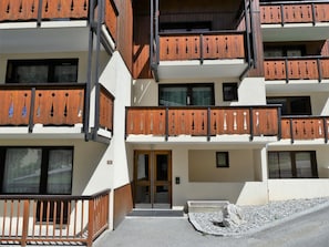 A multi-story building with balconies, a door, and a small garden area. - Ideal mezzanine studio - 4 guests (Pralognan-la-Vanoise)