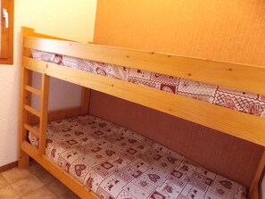 Ein Stockbett mit einer Leiter auf der linken Seite, einer gemusterten Matratze und einem Holzkopfstück.