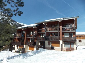 Ein mehrstöckiges Holzhaus mit Balkonen, umgeben von Schnee und Bäumen.