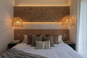 A hotel room with a bed, two bedside tables, a wall with geometric patterns, and two hanging lamps. - Lux 1BR  Ocean-View Pool  w/Habitas Beach Club (Tulum)