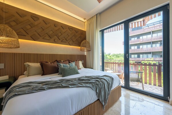 Quarto de hotel moderno com cama grande, cabeceira de madeira e varanda com vista para um edifício.