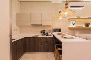A modern kitchen with a central island, wooden cabinets, a built-in microwave, and a hanging light fixture. - Lux 1BR  Ocean-View Pool  w/Habitas Beach Club (Tulum)