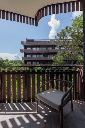A balcony with a chair, a view of a multi-story building, and a clear sky. - Lux 1BR  Ocean-View Pool  w/Habitas Beach Club (Tulum)
