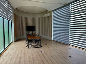 A conference room with a wooden table, chairs, a flat-screen TV, and a ceiling with a circular design. - Lux 1BR  Ocean-View Pool  w/Habitas Beach Club (Tulum)