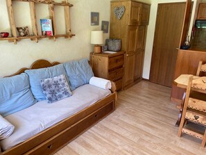 A wooden bed with a headboard, a wooden wardrobe, a wooden chair, and a wooden shelf with books and a lamp. - Charming apartment without equipment - 4 guests (Pralognan-la-Vanoise)