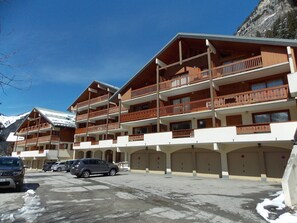 A multi-story hotel with balconies, a parking area, and snow on the ground. - Sunny apartment - 4 guests (Pralognan-la-Vanoise)