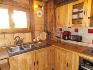 Une cuisine de style rustique, avec des éléments en bois, comprenant un évier, un grille-pain et une machine à café.