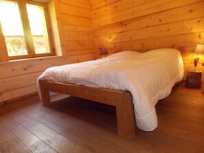 A wooden cabin bedroom with a bed, a nightstand, and a window. - Chalet, pets allowed - 8 guests in quiet area (Pralognan-la-Vanoise)