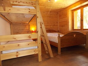 Une cabane en bois avec un lit superposé et un lit simple.