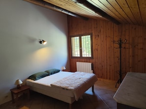 A bedroom with a bed, bedside table, lamp, window, coat rack, and wooden walls. - Balcon du Pontillas, garden, ski/bike storage, 400 m from slopes, shuttle 100 m (La Salle-les-Alpes)