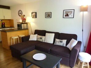 A living room with a sofa, a coffee table, and a kitchen area with a microwave and a kettle. - Stylishly renovated apartment near slopes - 4 guests (Pralognan-la-Vanoise)