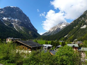 A mountain village with traditional wooden houses, a clear sky, and snow-capped peaks in the background. - Stylishly renovated apartment near slopes - 4 guests (Pralognan-la-Vanoise)