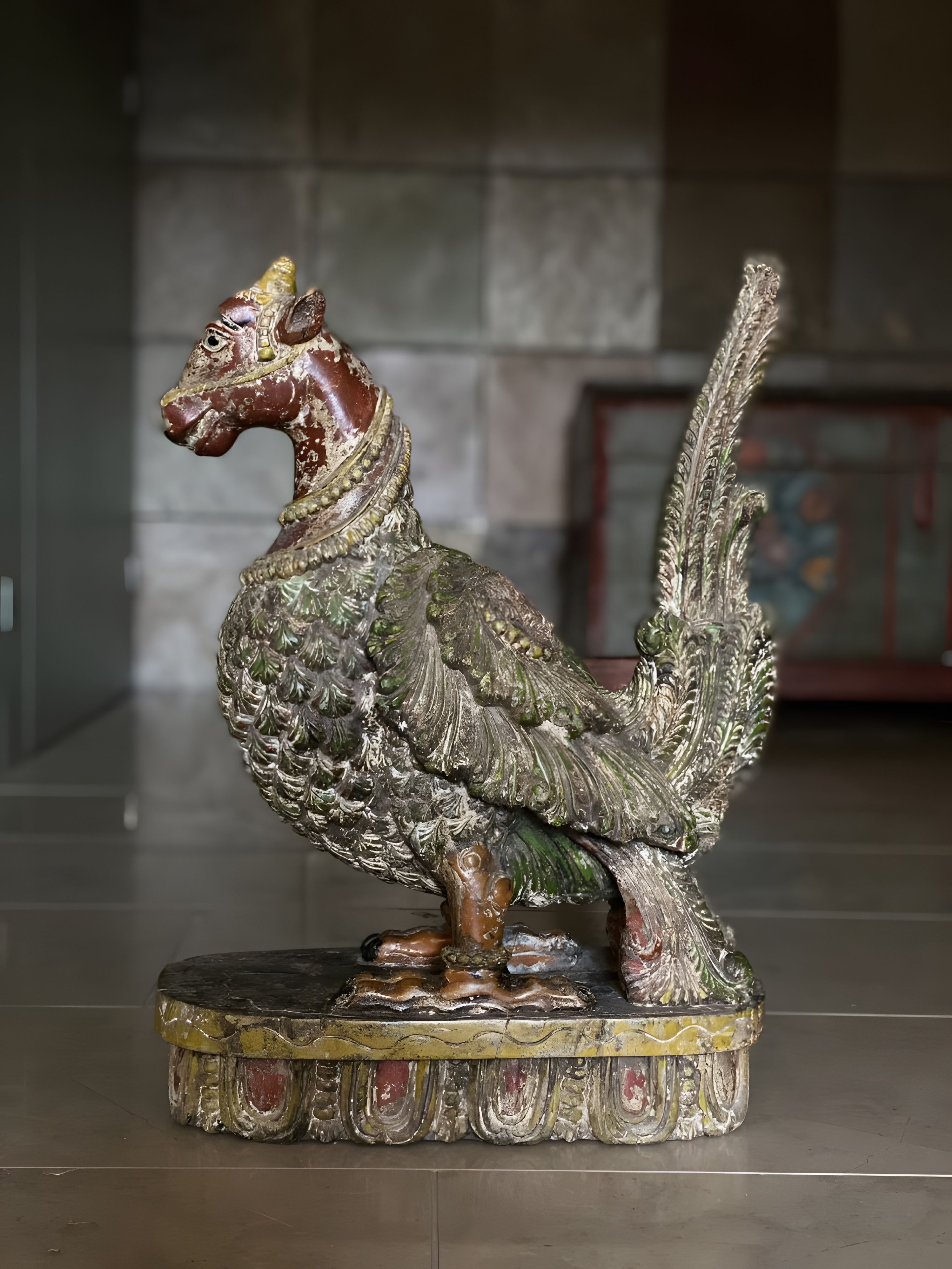 A detailed sculpture of a bird-like creature with intricate patterns, standing on a decorative base.