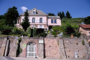 A historic building with a stone wall entrance, a sign indicating 'Chambres Zimmer,' and a traditional gate.