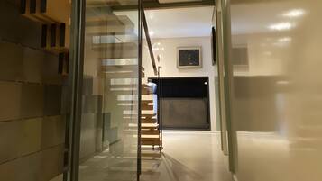 Un interior moderno con una escalera de cristal que lleva a un espacio de tonos oscuros.