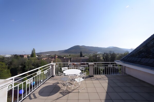 Een balkon met een tafel en stoelen, met uitzicht op een bergachtig landschap.