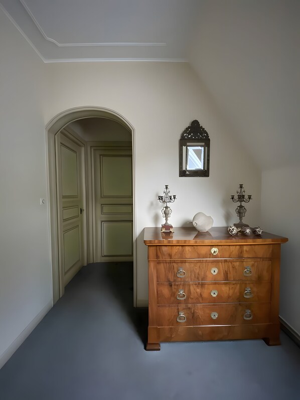 Un pasillo con un aparador de madera, un espejo y una puerta que da a otra habitación.