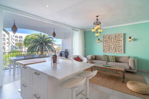 A modern living room with a balcony, a dining area, and a kitchen. - Apartment in Nerja Near Carabeillo Beach (Nerja)