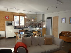 A cozy living room with a sofa and chairs, a dining table, and a kitchen area with a microwave, stove, and refrigerator. - Quiet chalet - 6 guests (Pralognan-la-Vanoise)