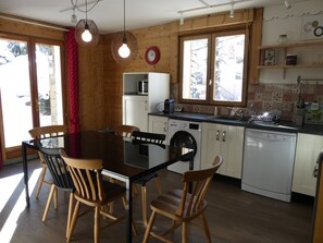 Eine kleine Küche mit Essbereich, Holzwänden und Blick durch das Fenster.