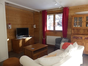A cozy living room with a television, wooden furniture, a sofa, and a cabinet with glass doors. - Quiet chalet - 6 guests (Pralognan-la-Vanoise)