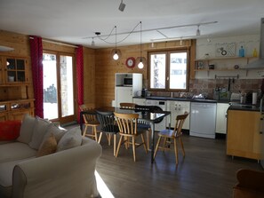 A cozy living room with a sofa and chairs, a dining area with a table and chairs, and a kitchen with wooden cabinets and a microwave. - Quiet chalet - 6 guests (Pralognan-la-Vanoise)
