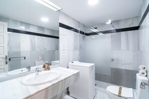 A modern bathroom with a large mirror, a sink, a toilet, and a shower. - Apartment in Nerja Near El Playazo Beach (Nerja)