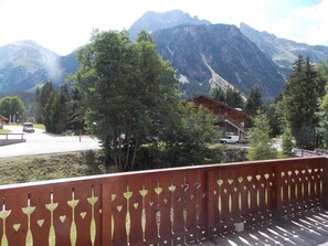 A mountain lodge with a wooden deck and a view of the surrounding mountains. - Charming apartment near center - 4 guests (Pralognan-la-Vanoise)