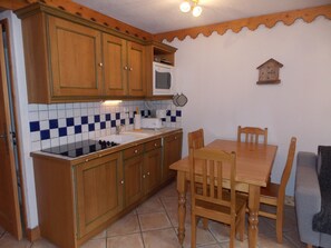 Eine Küche mit Holzausstattung, einer Mikrowelle, einem Spülbecken und einem Esstisch mit Stühlen.