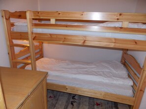 Ein Stockbett mit Holzrahmen und weißer Bettwäsche.