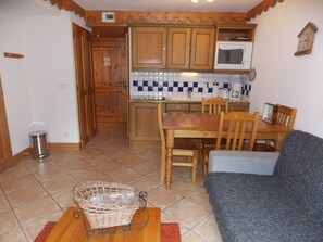 A compact kitchen with wooden cabinets, a microwave, and a tiled backsplash. - Charming apartment near center - 4 guests (Pralognan-la-Vanoise)