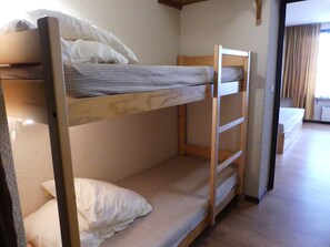 A bunk bed with a wooden frame and a mattress with a checkered pattern. - Comfortable central studio - 4 guests (Pralognan-la-Vanoise)