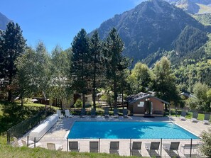 A swimming pool with lounge chairs and a small building, surrounded by trees and mountains. - Studio cabin, pets welcome - 4 guests (Pralognan-la-Vanoise)