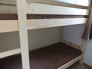 A bunk bed with a wooden frame and a mattress. - Studio cabin, pets welcome - 4 guests (Pralognan-la-Vanoise)