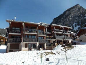A multi-story hotel with balconies, set against a mountainous backdrop. - Studio cabin, pets welcome - 4 guests (Pralognan-la-Vanoise)