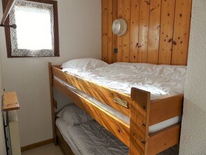 A bunk bed with a wooden frame and a window with lace curtains. - Well-located studio cabin, cats OK - 4 guests (Pralognan-la-Vanoise)