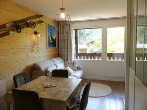 Una habitación acogedora con pared de madera, un sofá, una mesa de comedor y una ventana con vistas a zonas verdes.