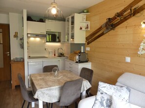 A compact kitchen with white cabinets, a coffee machine, and a wooden staircase. - Cozy cabin studio - 4 guests (Pralognan-la-Vanoise)