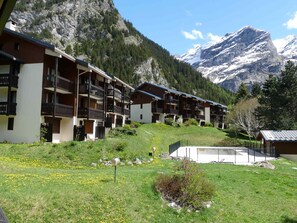 Un complejo turístico de montaña con edificios de varios pisos, balcones y una vista despejada de montañas nevadas.