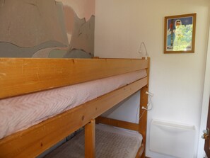 A bunk bed with a wooden frame and a white mattress. There is a wall-mounted radiator and a framed map on the wall. - Cozy cabin studio - 4 guests (Pralognan-la-Vanoise)