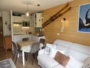 A cozy interior with a dining area, a sofa, and a kitchen. - Cozy cabin studio - 4 guests (Pralognan-la-Vanoise)