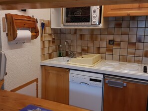 Eine kompakte Küche mit Geschirrspüler von Bosch, einem Einbauofen und einem Spülbecken.