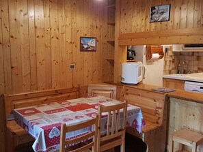 Un intérieur en bois avec une table dressée pour deux personnes, un four à micro-ondes et un petit coin cuisine.