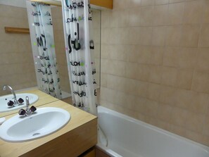 Een badkamer met een wit wastafelmeubel, spiegel en bad.