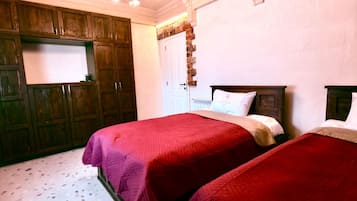 A room with two beds, wooden cabinets, a chandelier, and a white door.